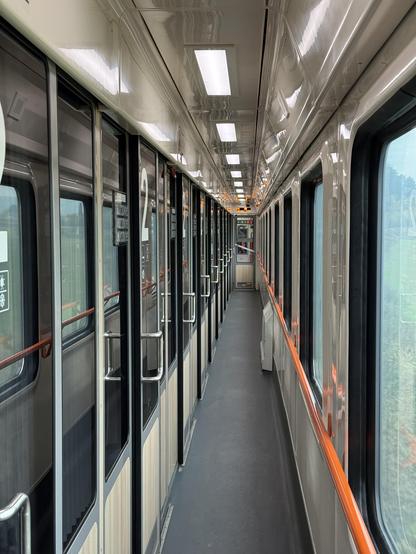 Corridor view of a train carriage. Cabines left, windows right.