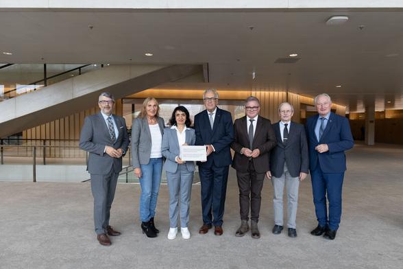 Landtagspräsidentin Muhterem Aras  überreicht eine Gravurplakette an den Vorsitzenden des Vereins für das Nationaldenkmal Hartmannswillerkopf, Jean Klinkert.