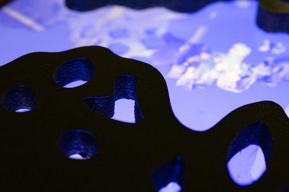 écran montrant un paysage bleue en dessous d'une structure en bois noir, intérieur du banc