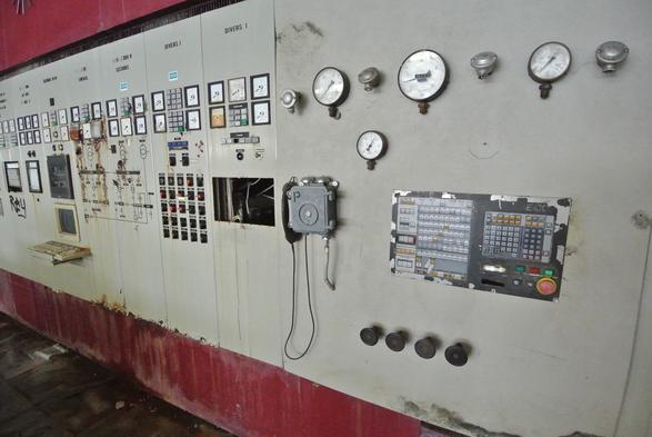 Kontrollwand eines verlassenen Kraftwerkes.
Diese ist voll mit analogen Uhren und Anzeigen, habtischen Knöpfen und co. Die Wand ist Grau und die Korrosion hinterlässt erste Spuren. Oben und unten ist die Wand tief rot gestrichen