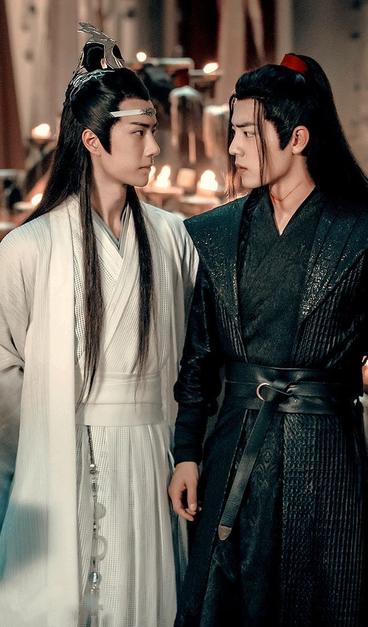 Lan Wangji and Wei Wuxian, standing side by side, exchange a look of concern during the Guanyin temple scene.