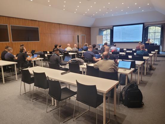 A workshop room full of nerds with laptops watching a presentation as part of a workshop on .NET Aspire