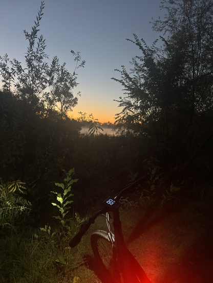 Vapor rising from the nature trail side of Boise Cascade Lake. Orange sunrise in the background, my bike with red taillight in the foreground.