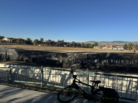 The flattened River District dirt behind the construction fence, my bike in the foreground.
