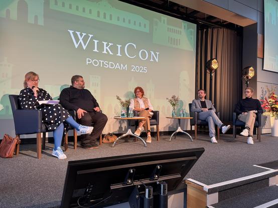 5 Menschen auf einem Podium während einer Diskussionsrunde im Rahmen der WikiCon 2025 in Potsdam
