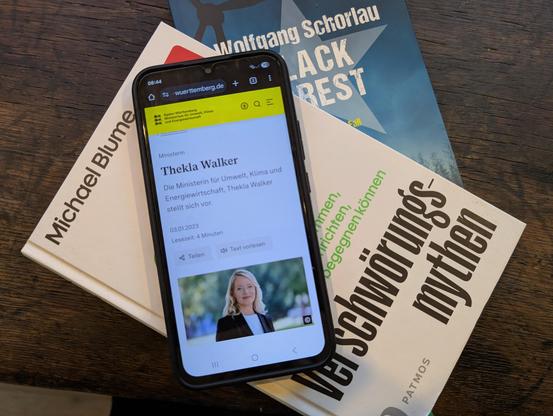Ein Smartphone mit einer Ankündigung von Thekla Walker liegt auf den Büchern "Verschwörungsmythen" von Michael Blume und "Black Forest" von Wolfgang Schorlau.