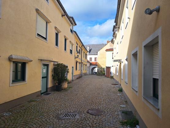 Gepflasterte Straße zwischen gelben Häusern.