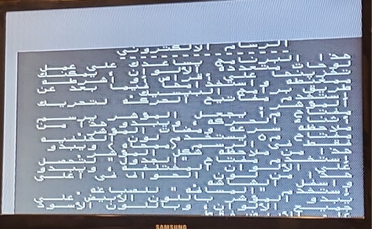 a monitor showing some output from the microcomputer using the Arabic codepage. the image is not centered, and the low fidelity characters are difficult to read. the text is introducing a drawing program that uses simple cursor movement and pen-up pen-down style controls. you can select from a couple different pen and background colors.