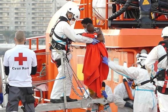 Un miembro de la Cruz Roja ayuda a un niño migrante a bajar del barco, en el puerto de Arguineguín, en Gran Canaria, España. (Europa Press via Getty Images)