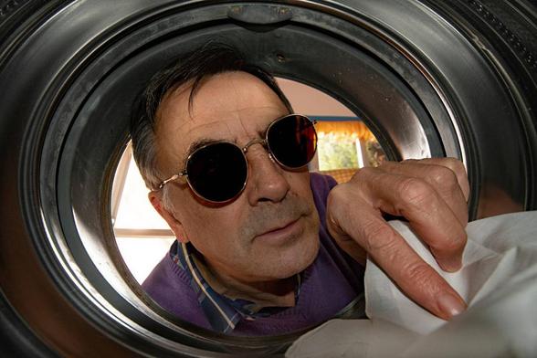 Un hombre con gafas de sol observa con curiosidad el interior de la lavadora (Getty Images)