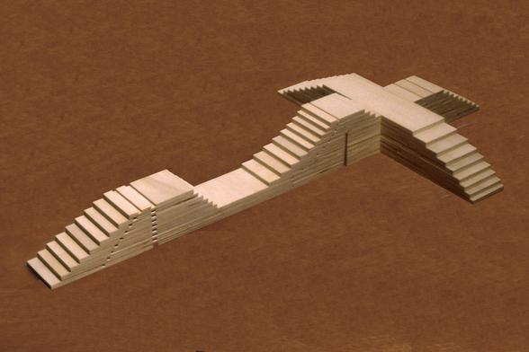 Ступенчатая архитектурно-геометрическая скульптура из тополиной фанеры. Конструкция напоминает бруталистский макет с тремя короткими и одним длинным крылом, скульптура имеет чётную симметрию, а самая высокая часть — пологая вершина — сложена из 12 фанерных плит. // A stepped architectural geometric sculpture made of poplar plywood. The structure resembles a brutalist model with three short wings and one long one. The sculpture has an even symmetry, and its highest part — the gently sloping top — is composed of 12 plywood slabs. // Jackie Ferrara, “Cross Crete”, 1979–1981, poplar plywood, 66 × 38 × 8 cm // 1981 © Jackie Ferrara