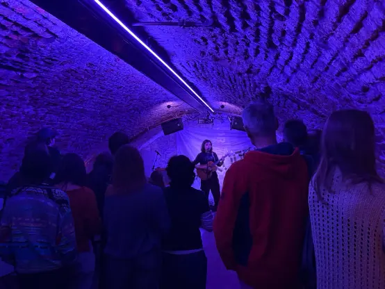 A purple coloured cellar where a guy is playing guitar and singing