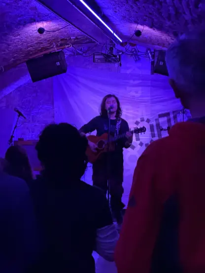 a guy playing guitar in purple light