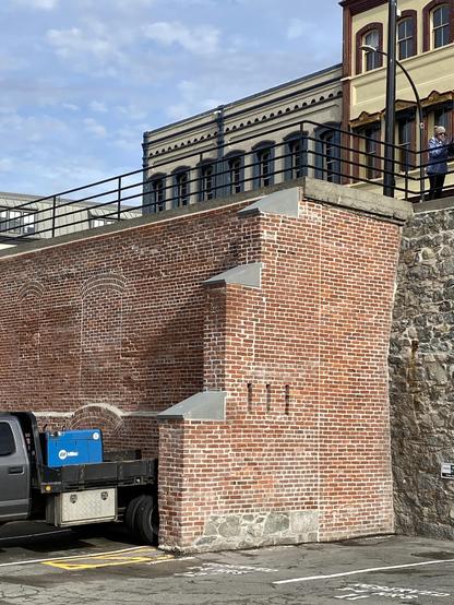 Brick wall of a demolished warehouse, with loopholes and cap facings