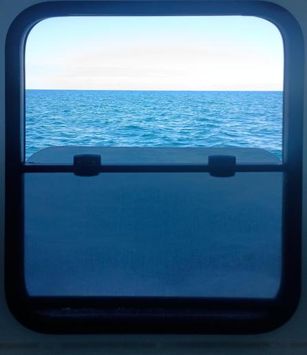 A blank ocean view, seen through a half open window.