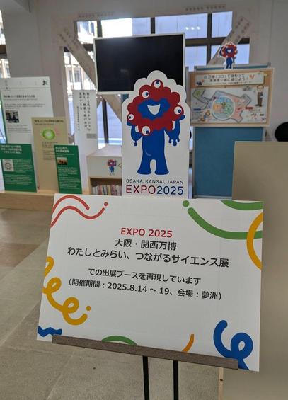 A cardboard cut out of Myaku-Myaku with a sign in Japanese explaining that this is a recreation of the booth that was at Osaka Expo.