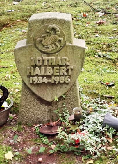 Tombstone made of light stone, stylized cross with coat of arms depicting a scorpion.