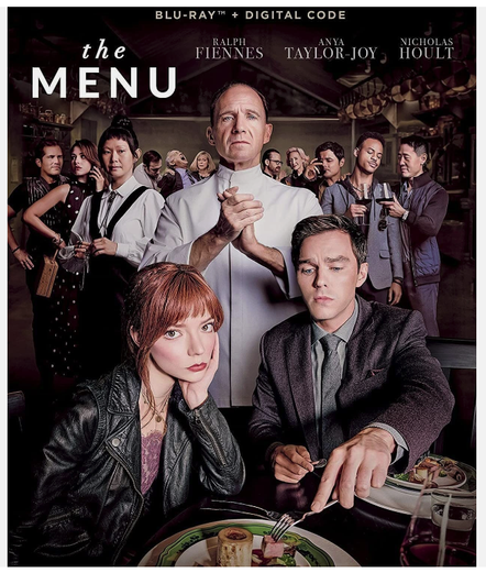 Cover of Blue Ray disk of the Menu. Ralph Fiennes stands behind Ann Taylor Joy and Nicholas Hoult sifting at a table (Hoult is helping himself to her food) while the rest of the cast stands in the background.