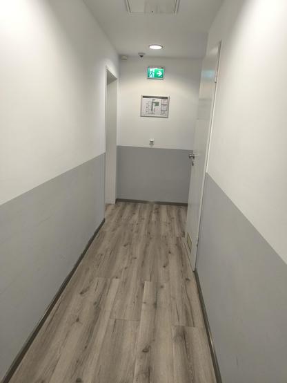 Leerer Hotelflur mit braunem Laminat und weißen Wänden. Leider nicht sehr einladend.