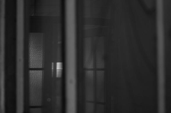 Fensterspiegelung mit mehreren vertikalen und horizontalen Rahmenstrukturen in dunkler, reduzierter Transparenz.