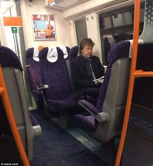 The picture is of Paul McCartney sitting and reading a book whilst travelling on a train.