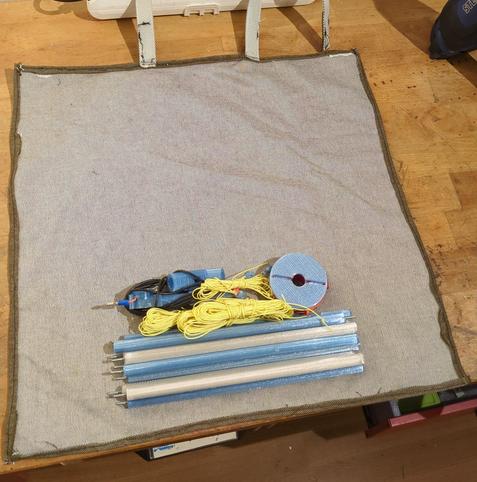 A rectangular cloth on a workbench. There are some 3d printed rods and strings are in the middle.