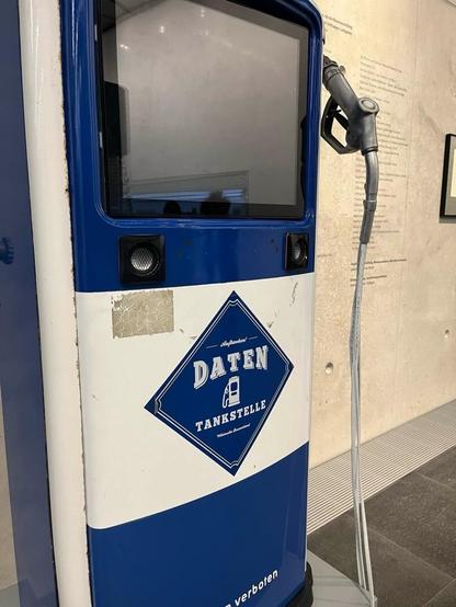 KI generiert, bearbeitet: Das Bild zeigt eine blaue Zapfsäule. Die weiß-blaue Zapfsäule ist mit einem blauen Rechteck mit dem Text "DATEN" und "TANKSTELLE" verziert. Darüber ist ein dunkler, ausgeschalteter Bildschirm. Rechts befindet sich ein schwarzer Tankschlauch, der rechts an der Säule hängt. Der Hintergrund des Bildes besteht aus einer hellgrauen Beton-Wand auf der ein Ausstellungstext steht.
Bereitgestellt von @altbot, privat und lokal generiert mit Gemma3:12b
🌱 Energieverbrauch: 0.384 Wh