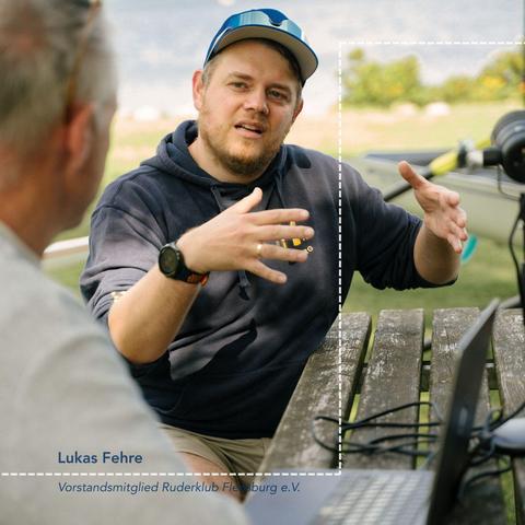 Eine männliche Person gestikuliert und erklärt im Gespräch im Freien.
