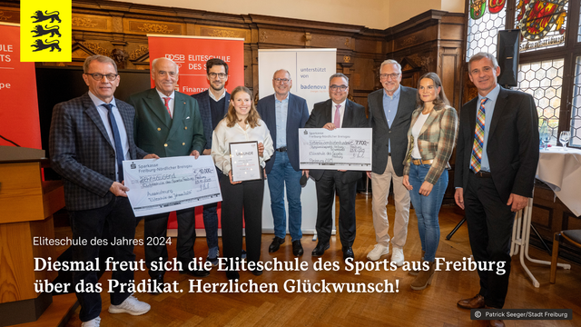 Gruppenbild von der Verleihung der Auszeichnung "Eliteschule des Jahres 2024" im Ratssaal der Stadt Freiburg.
Aufschrift: Eliteschule des Jahres 2024. Diesmal freut sich die Eliteschule des Sports über das Prädikat. Herzlichen Glückwunsch!