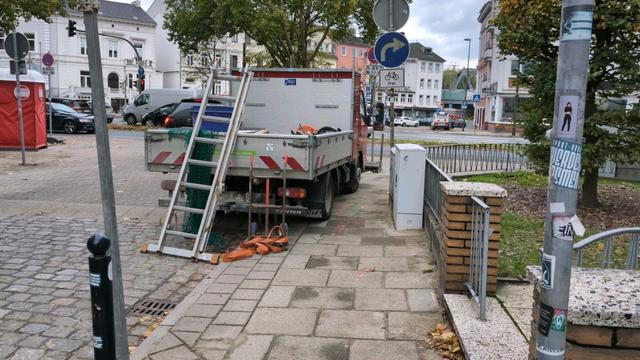Nähere Ansicht des einen Handwerkerwagen. Vom Gehweg bleibt zwischen Verteilerkasten und Fahrzeug nur noch ein sehr schmaler Durchgang.
