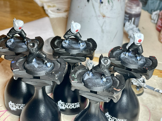 Five headless and armless t’au pathfinders, halfway painted, each on their own painting stand.
