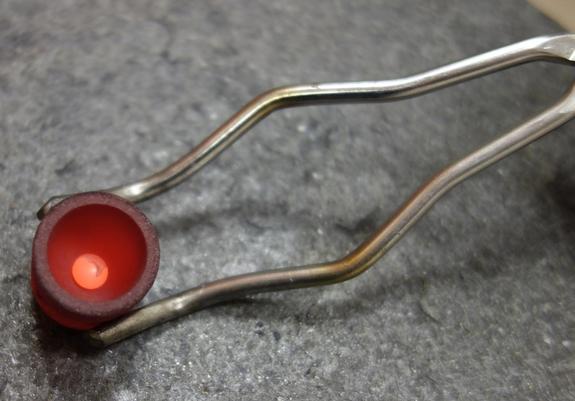 Ce creuset en graphite sort du four, où la poudre de roche a fondu. Il ne reste plus qu’à jeter cette perle incandescente dans une solution acide pour la transformer en un liquide prêt à être analysé. CC BY Jean-Marie Prival / kīpuka.