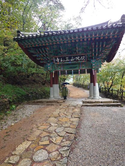 the entrance door/shrine to the temple complex. my son with an umbrella and a poncho under it.