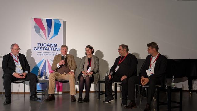 Fünf Personen sitzen an einem Tisch auf einer Bühne. Die Personen tragen alle Anzüge oder Kostüme, und einige tragen Namensschilder. Hinter den Personen befindet sich ein Banner mit dem Text "GESTALTEN Mehr kulturelle Vielfalt". Jede Person sitzt an einem ihrer Platz und blickt nach vorne. Eine Kamera ist auf dem Tisch zwischen den Personen platziert. Die Beleuchtung ist auf die Personen und das Banner gerichtet. 

Bereitgestellt von @altbot, privat und lokal generiert mit Gemma3:12b

🌱 Energieverbrauch: 0.372 Wh