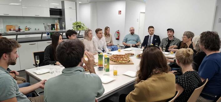 Attendees sit at a big table in the kitchen, eat and chat. Photo credit: Digital Science Center/Universität Innsbruck.