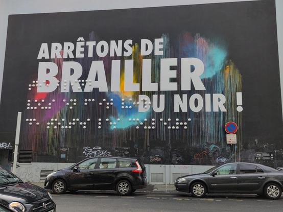 L'oeuvre est un immense rectangle noir sur tout le mur, avec tâches de couleurs variées qui dégoulinent, puis par-dessus des grands caractères blancs "Arrêtons de brailler du noir !" et le faux braille sous forme d'énormes demi-sphères blanches.