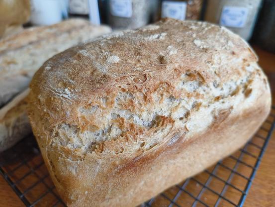 A crusty sandwich loaf, cooling on a rack.