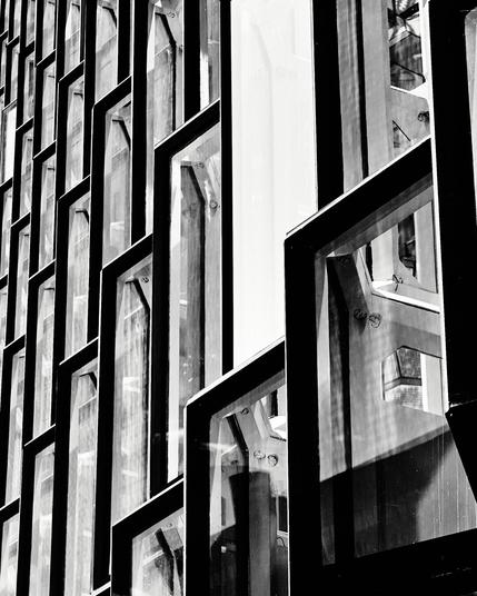 This black and white photograph captures the intricate geometric design of Harpa's facade in Reykjavik. The play of light and shadow across the glass panels creates a dynamic and bold visual effect, showcasing architectural elegance in monochrome.