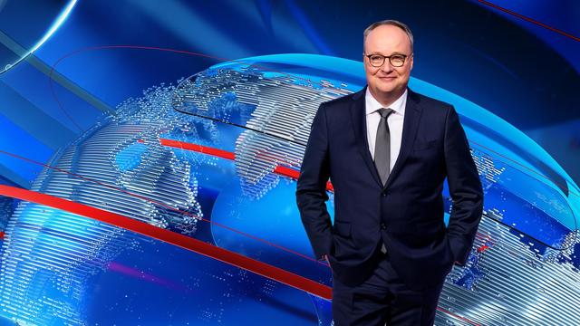 Heute-show-Moderator Oliver Welke im Anzug vor einer grafisch dargestellten Weltkugel.