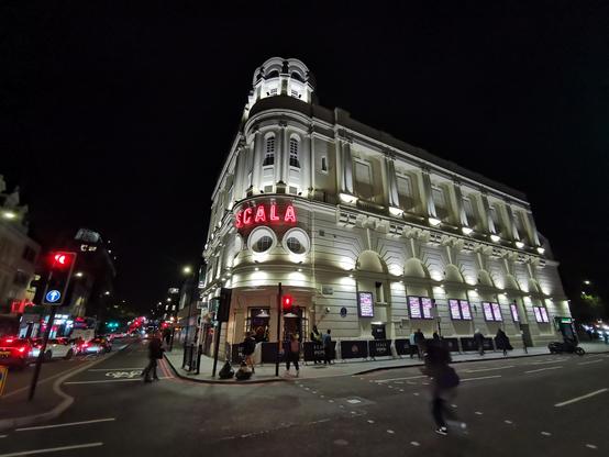 Scala venue in King's Cross London. White building on a street corner. The signage for Scala is red neon.