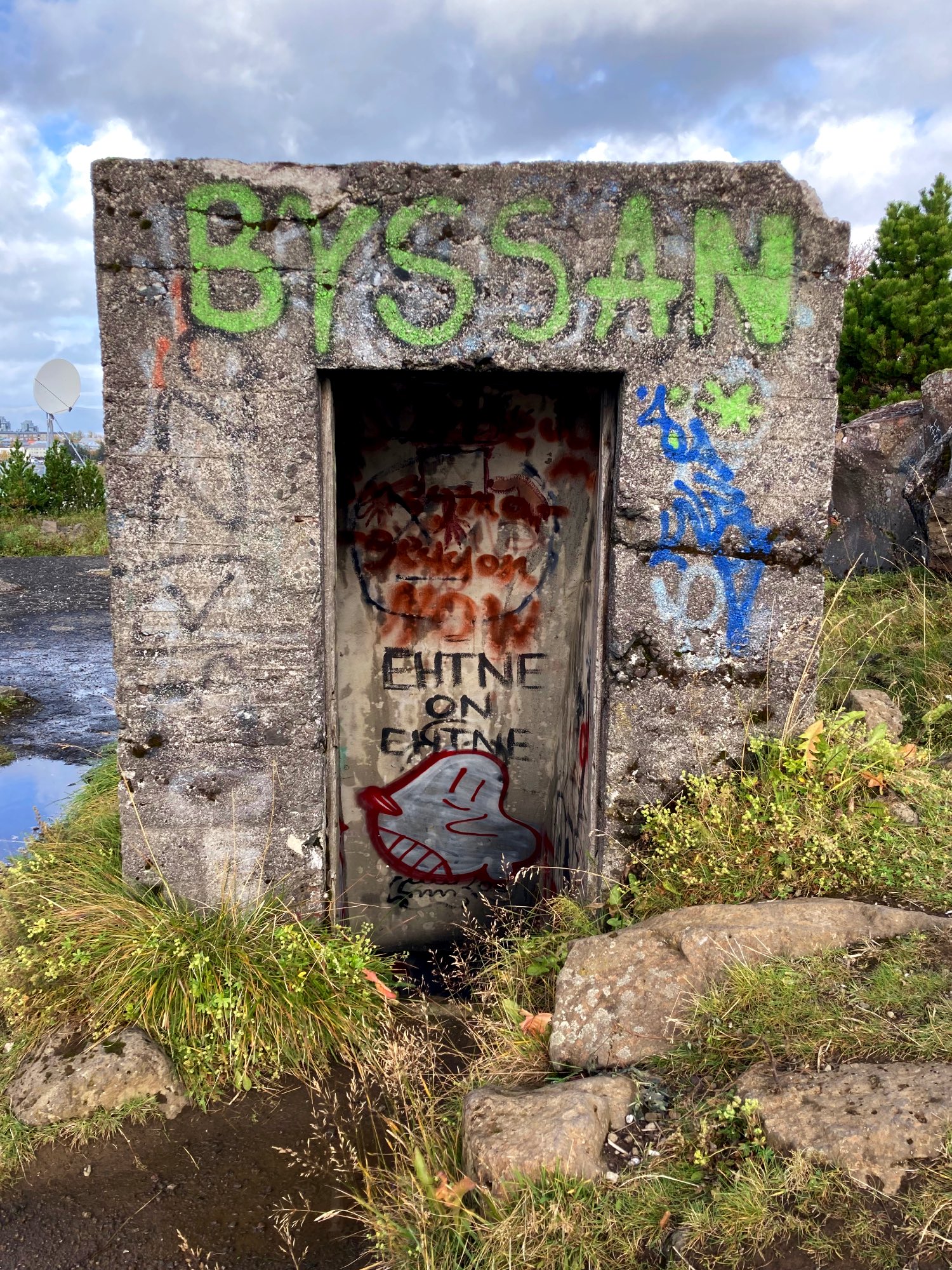 An entrance to a Wold War II bunker covered in graffiti.