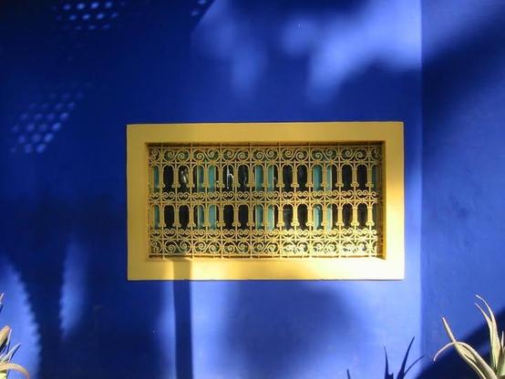 Now, having said that. A wall painted a rich, sky blue, and a golden-yellow window with intricate, delicate grillwork.