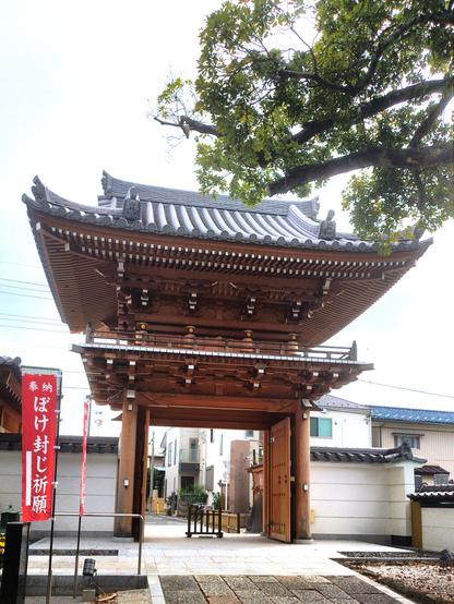 A big entrance gate with a top floor balcony and an intricate curved roof. The picture was taken on the temple grounds looking out at the street.