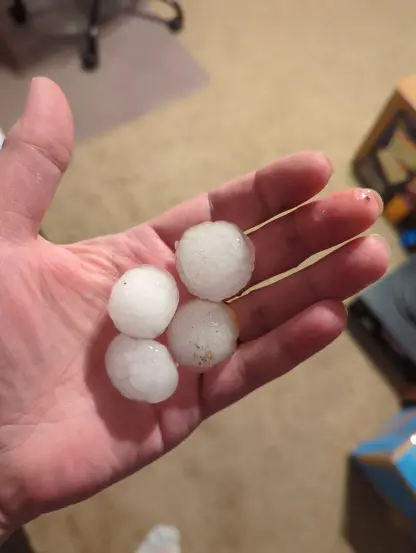 A hand holing four 1 inch hailstones.