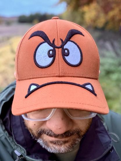 Goomba hat! His eyes are on the front and his toothy mouth on the bit that covers your eyes, whatever that’s officially called. The flap?