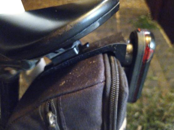 Is bike saddle with saddlebag underneath. Rear light is mounted on thin strip of black plastic that is sandwiched between two pieces of attachment of seat bag to saddle.