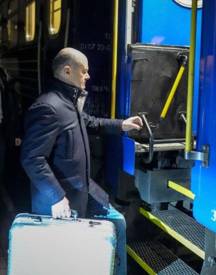 Olaf Scholz steigt mit einem Koffer in eine Eisenbahn.