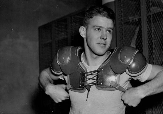 Gopher QB Bud Wilkinson puts on pads in the locker room before a game circa 1935.