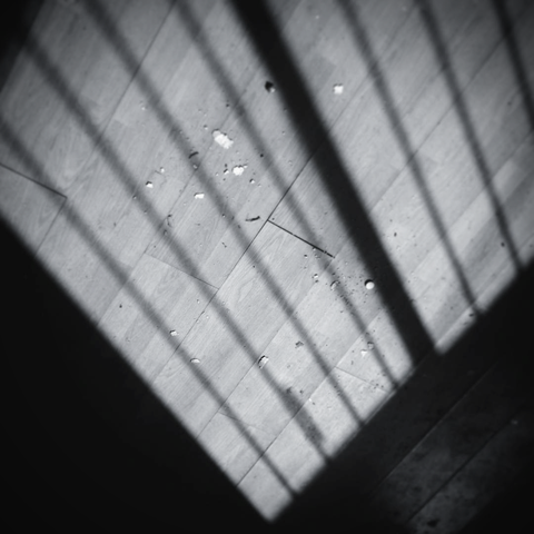 A V shaped light pattern over a dirty old wooden floor