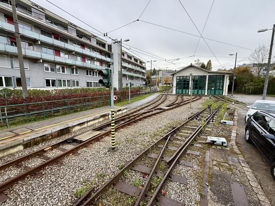Gleisvorfeld des Talbahnhofs mit der Remise auf der gegenüberliegenden Seite. Das rechts Gleis verläuft nur zwischen Remise und Bahnsteig, die abgetrennten Weichen sind noch erkennbar. Links von der Remise führt die Anbindung zur Strecke vorbei.